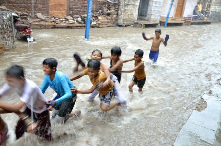Téléchargez les photos : Garçons jouant eau courante de mousson sur la route Jodhpur Inde - en image libre de droit