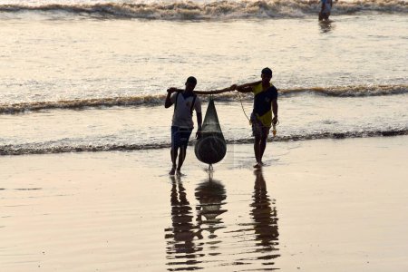 Téléchargez les photos : Pêcheur transportant du poisson du bateau à Uttan Beach, Bhayandar, Mumbai, Maharashtra, Inde, Asie - en image libre de droit