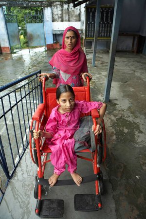 Téléchargez les photos : Femme poussant fauteuil roulant de fille handicapée physique initiative socio-économique par l'ONG Chinmaya Organisation de développement rural CORD, Sidhbari, Himachal Pradesh, Inde - en image libre de droit