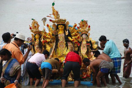 Téléchargez les photos : Des dévots plongeant le modèle Durga dans la rivière - en image libre de droit