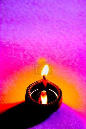 Schöne Kunst, eine einzige Diya-Ton-Öllampe eine Lichtquelle als Flamme auf buntem Hintergrund
