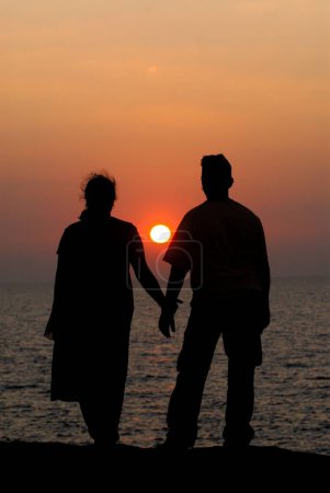 Photo for Couple , Husband and Wife watching Sunset holding their hands at Harihareshwar Beach , Konkan Region Raigad - Royalty Free Image