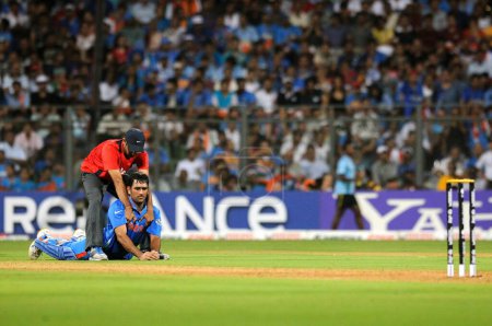 Photo for Indian captain batsman M S Dhoni receives treatment from the physio during the 2011 ICC World Cup Final between India and Sri Lanka at Wankhede Stadium on April 2 2011 in Mumbai India - Royalty Free Image