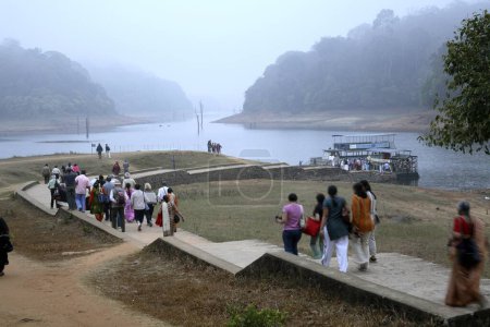 Téléchargez les photos : Tôt le matin touristes se dirigeant vers bateau Jetty pour une promenade en bateau au lac Periyar, sanctuaire de la faune Periyar, Thekkady, Kerala, Inde - en image libre de droit