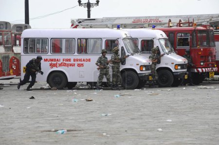 Téléchargez les photos : Ambulance ; Pompiers Van et garde de sécurité nationale commandos NSG dans une position à l'extérieur de l'hôtel Taj Mahal ; après l'attaque terroriste par Deccan Moudjahidin le 26 Novembre 2008 à Bombay Mumbai ; Maharashtra ; Inde - en image libre de droit