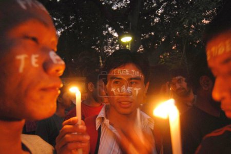 Téléchargez les photos : Tibétains peints visage protestant en tenant des bougies contre la répression chinoise au Tibet à Bombay Mumbai, Maharashtra, Inde - en image libre de droit