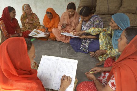 Foto de Mujeres voluntarias de la ONG Chinmaya Organización de Desarrollo Rural CORD recogen contribución de miembros de Micro Credit Finance, Sidhbari, Himachal Pradesh, India - Imagen libre de derechos