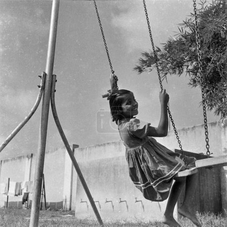 Photo for Old vintage 1900s black and white picture of Indian girl child on swing children playground India 1940s - Royalty Free Image