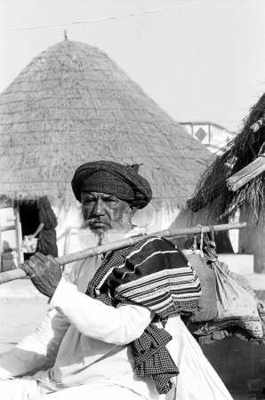 Foto de Rabari anciano con un enorme casco que lleva poste de bambú con una pequeña bolsa de comida atada extremo tono, Gujarat, India - Imagen libre de derechos