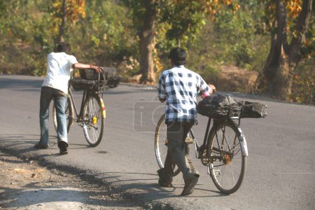 Téléchargez les photos : Travailleurs d'une mine de charbon transportant une masse de charbon chargé siège arrière de bicyclettes dans le Jharkhand ; Inde - en image libre de droit