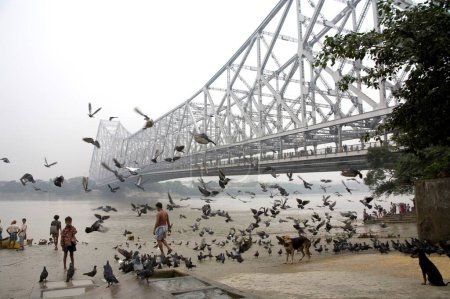 Foto de Actividades en Babu ghat; puente Howrah sobre el río Hooghly en el fondo; Calcuta ahora Kolkata; Bengala Occidental; India - Imagen libre de derechos