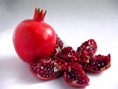 Frutas, una granada sin cortar completa una fruta de comida medio cortada sobre fondo gris