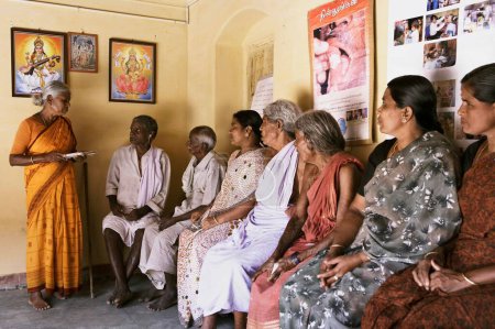 Foto de Trabajador sanitario de la ONG Chinmaya Organización de Desarrollo Rural CORD dando instrucciones de salud a pacientes rurales que esperan en el centro de salud, Siruvani, Karnataka, India - Imagen libre de derechos