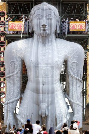 Téléchargez les photos : Verser du lait sur 58,8 pieds monolithique pleine longueur statue de jain saint Gomateshwara seigneur Bahubali dans Mahamastakabhisheka tête cérémonie d'onction ; Sravanabelagola, Karnataka, Inde - en image libre de droit
