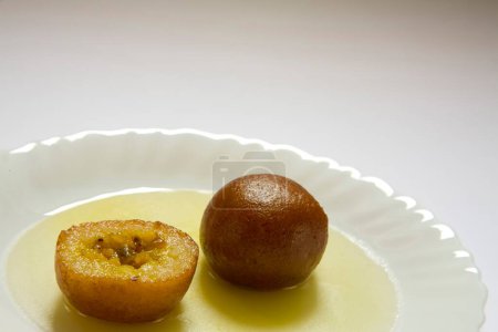 Photo for Indian sweet food one and half piece of round shape Gulabjamun Bonbon Confectionery with sugar syrup served in plate - Royalty Free Image