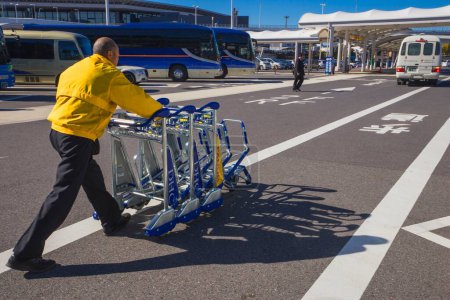 Téléchargez les photos : Homme poussant des chariots à bagages, aéroport international de Narita, Tokyo, Japon - en image libre de droit