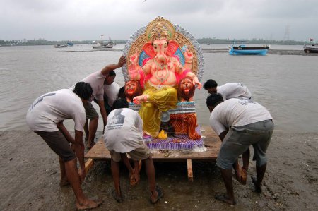 Téléchargez les photos : Les dévots plongent une énorme idole de Ganesh dans la mer à Versova, Bombay Mumbai, Maharashtra, Inde - en image libre de droit