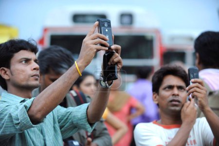 Téléchargez les photos : Des touristes prennent des photos sur mobile devant l'hôtel Taj Mahal, après l'attaque terroriste de Deccan Moudjahidine le 26 novembre 2008 à Bombay Mumbai, Maharashtra, Inde - en image libre de droit