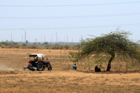 Téléchargez les photos : Tracteur dans un champ sec avec moulins à vent à l'arrière ; Kutch ; Gujarat ; Inde - en image libre de droit