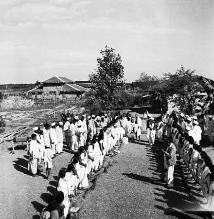 Téléchargez les photos : Les étudiants du centre de formation pour femmes Mahila Ashram fondé par Jamnalal Bajaj rencontrent Mahatma Gandhi devant sa cabane à l'Ashram de Sevagram après la campagne de nettoyage du village, 1941 - en image libre de droit