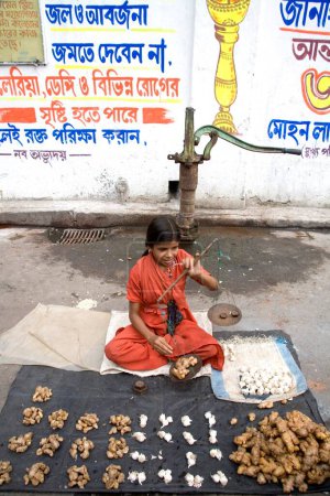 Téléchargez les photos : Fille mesurant l'ail et le gingembre à l'échelle du poids sur le marché des légumes ; Siyaldah ; Calcutta maintenant Kolkata ; Bengale occidental ; Inde - en image libre de droit