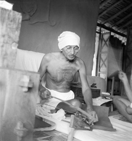 Téléchargez les photos : Mahatma Gandhi tournant dans sa cabane à l'Ashram de Sevagram, Vardha, Maharashtra, Inde, 1940 - en image libre de droit