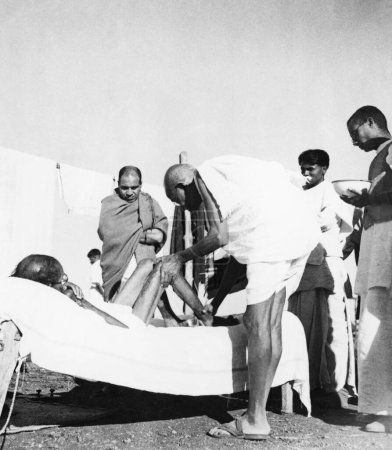 Téléchargez les photos : Mahatma Gandhi donne un massage 15 min par jour au lépreux Parchure Shastri à l'ashram de Sevagram, 1940, travailleur shankaran à Sushila Nayars Kasturba Gandhi Hospital près de l'ashram de Sevagram - en image libre de droit