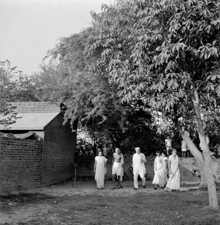Foto de Mahatma Gandhi caminando con Sushila Nayar, Sushila Pai, Abha Gandhi, Rajkumari Amrit Kaur y Abdul Kalam Maulana Azad en la Colonia Bhangi en Delhi, 1946, India - Imagen libre de derechos