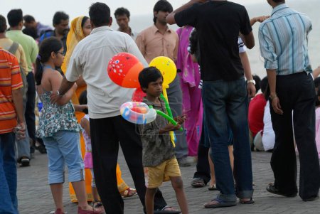 Téléchargez les photos : Un jeune garçon vend des ballons colorés à des touristes visitant Marine Drive à Bombay Mumbai, Maharashtra, Inde - en image libre de droit