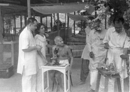Photo for Mahatma Gandhi observing a hookworm cell through a microscope Gandhigram Sumati Morarjees residence , Juhu Beach , Mumbai , May 1944 , Sushila Nayar , India - Royalty Free Image