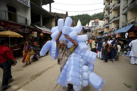 Foto de Una mujer que lleva un gran número de contenedores de plástico utilizados por los peregrinos para llevar el agua del Santo Ganges de vuelta a casa en Haridwar, Uttaranchal, India - Imagen libre de derechos