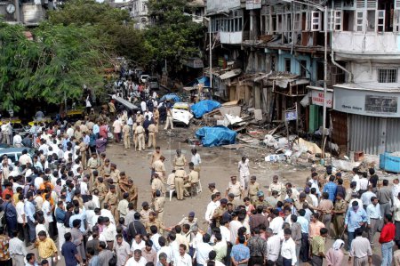 Téléchargez les photos : Des policiers inspectant le site de l'explosion ont également rassemblé un grand nombre de personnes pour regarder le site de Zaveri Bazaar dans la zone occupée de Kalbadevi ; Bombay Mumbai, Maharashtra, Inde Le 26 août 2003 - en image libre de droit