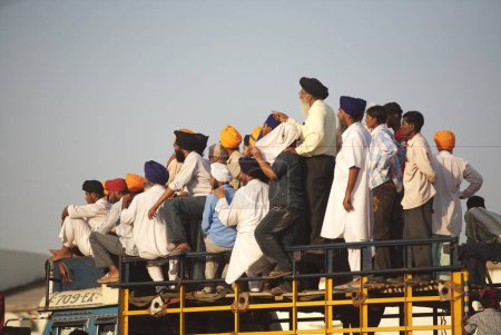 Téléchargez les photos : Dévots sikhs debout sur le dessus des cascades d'observation de camions de Nihangs ou guerrier sikhe, lors d'événements culturels pour les célébrations du 300e anniversaire de la consécration du perpétuel Sikh Guru Granth Sahib au terrain de sport Khalsa, Nanded, Maharashtra, Inde - en image libre de droit