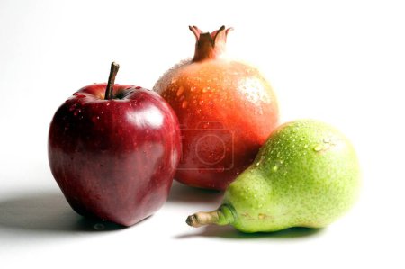 Foto de Frutas, gotas de agua sobre manzana, granada y pera sobre fondo blanco - Imagen libre de derechos