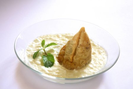 Foto de Comida rápida, samosa con cuajada y hojas de menta en tazón sobre fondo blanco - Imagen libre de derechos