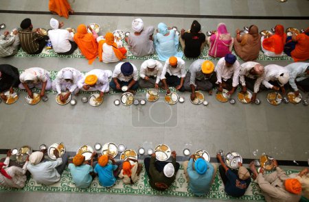 Photo for 300th year of consecration of Guru Granth Sahib on 30th October 2008, Sikh devotees having food at a Langar (traditional community kitchen) at Sachkhand Saheb Gurudwara, Nanded, Maharashtra, India - Royalty Free Image