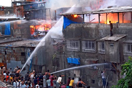 Téléchargez les photos : Pompiers aspergeant le feu avec un tuba dans les bidonvilles de Behrampada ; Bandra ; Bombay Mumbai ; Maharashtra ; Inde 18-juin-2009 - en image libre de droit