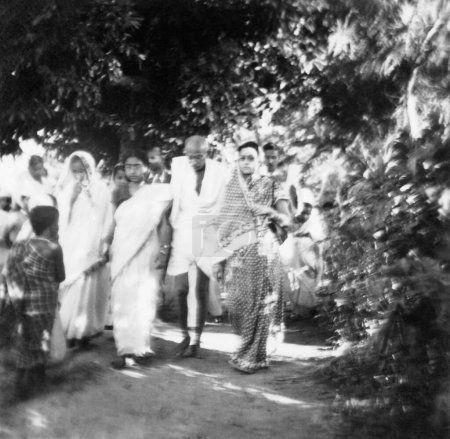 Foto de Mahatma Gandhi y otros caminando por el área afectada por disturbios hindúes musulmanes en Noakhali Bengala Oriental; Noviembre 1946; India - Imagen libre de derechos