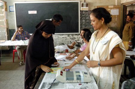 Photo for Muslim woman being identified before casting vote during the 2004 Indian Loksabha elections at polling booth at Shivaji Nagar, Govandi, Mumbai Bombay  Maharashtra, India - Royalty Free Image