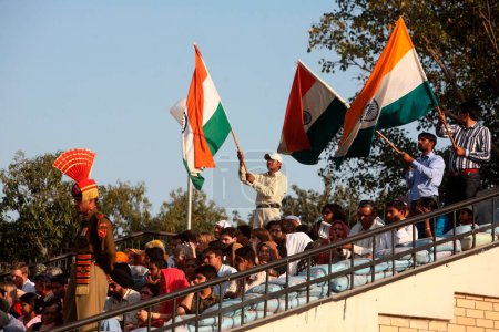 Foto de Multitud sosteniendo bandera india durante ceremonia de cambio de guardia en la frontera de Wagah, Amritsar, Punjab, India - Imagen libre de derechos