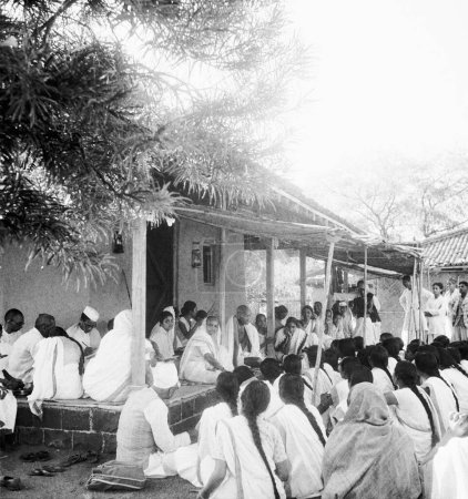 Foto de Mahatma Gandhi y Kasturba Gandhi hablando con chicas de Mahila Ashram Wardha, con motivo del aniversario de la rueda giratoria de Rantia Jayanti frente a la cabaña de Mahatma Gandhis en Sevagram Ashram, 1941, l de Kasturba Gandhi Abha Gandhi - Imagen libre de derechos