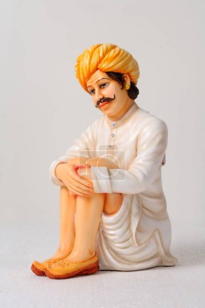 Foto de Figura de arcilla, estatua de hombre rajasthani usando dhoti y turbante en posición sentada - Imagen libre de derechos