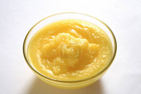 Foto de Ghee amarillo dorado casero granular puro en tazón de cristal sobre fondo blanco - Imagen libre de derechos