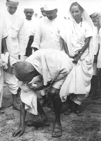 Photo for Mahatma Gandhi breaking the salt law by picking up a lump of natural salt at Dandi, Gujarat, India, April 6, 1930, 8.30 a.m. - Royalty Free Image