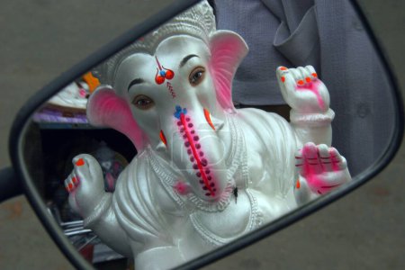 The image of the idol of Lord Ganesh; the elephant headed God ; in a mirror of a two wheeler ; Ganesh ganpati Festival ; Pune; Maharashtra; India
