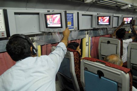 Téléchargez les photos : Voyageurs regardant la télévision introduire par Indian Railways sur une base expérimentale dans l'un des bogies climatisés à la gare centrale de Mumbai à Bombay Mumbai ; Maharashtra ; Inde - en image libre de droit