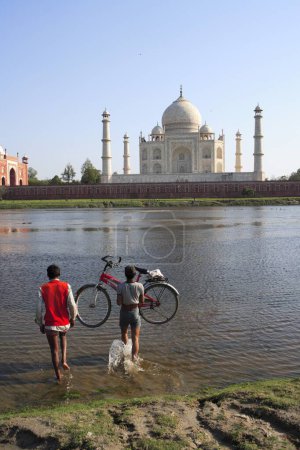 Photo for Man carrying bicycle in Yamuna River Taj Mahal Seventh Wonders of World , Agra , Uttar Pradesh , India UNESCO World Heritage Site - Royalty Free Image