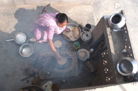 Foto de Un Punjaban (palabra usada para describir a la mujer Punjabi) haciendo rotis en la choolah de arcilla en la cocina abierta en casa; en Doulo Nangal; un pueblo cerca del río Beas; en el distrito de Amritsar; Punjab; India - Imagen libre de derechos