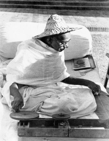 Photo for Mahatma Gandhi wearing a Noakhali hat whilst spinning at Birla House, New Delhi, India, November 1947 - Royalty Free Image