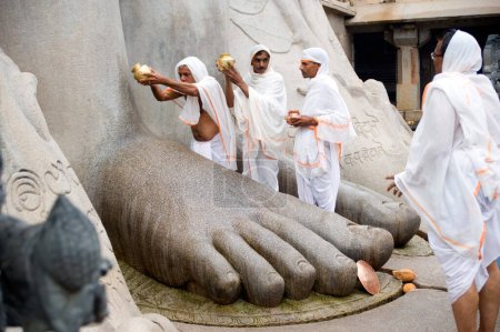 Téléchargez les photos : Verser de l'eau sur les pieds de la divinité jaïne gomateshvara, Sravanabelagola, Hassan, Karnataka, Inde - en image libre de droit
